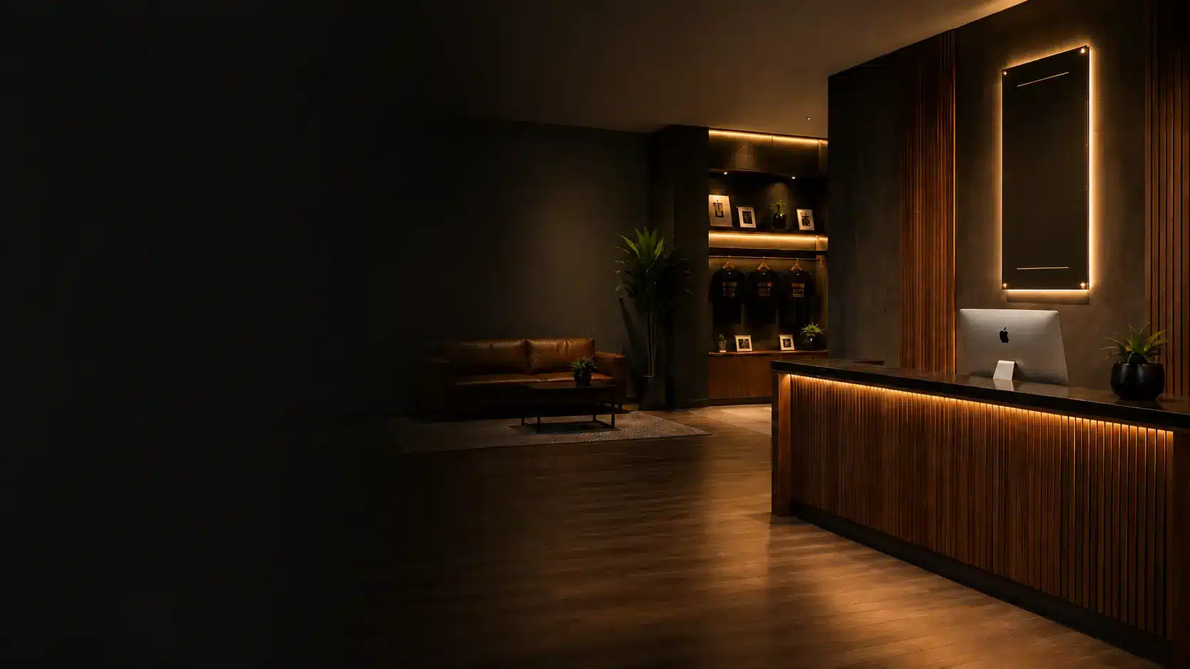 Warm, modern acting studio lobby with a wood reception desk, amber lighting, lounge seating, and display shelves.
