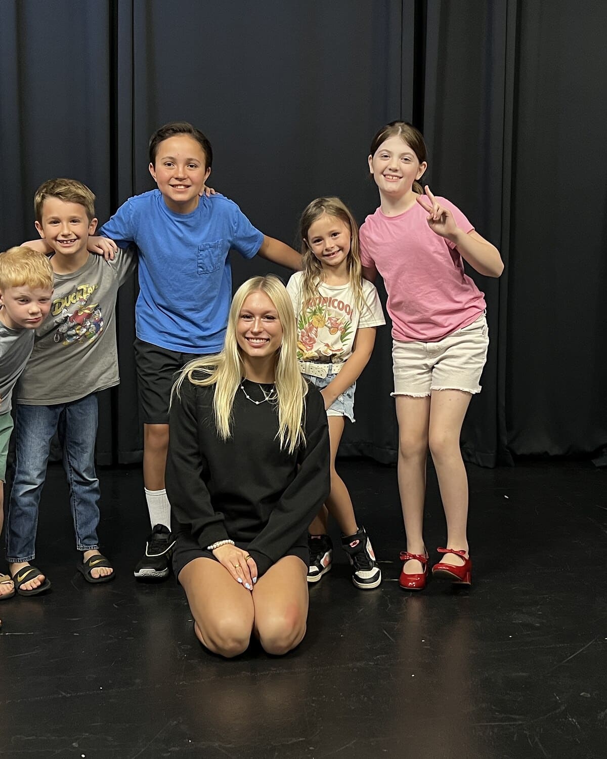 Six kid improv students with their coach on stage at Dearing Acting Studio