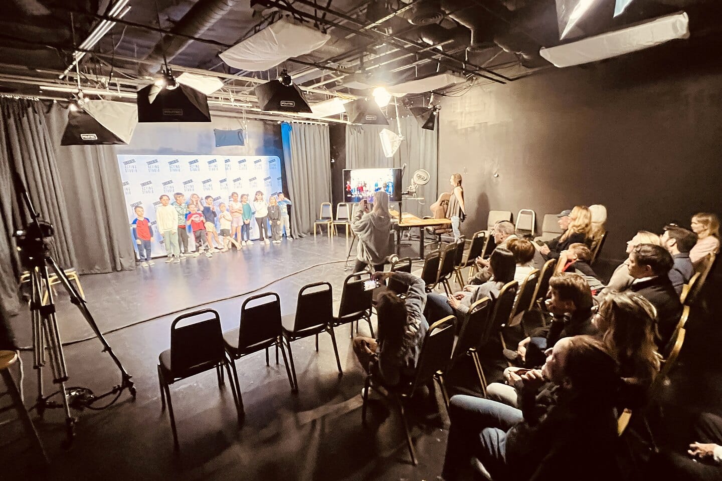 A kid improv showcase at Dearing Acting Studio, the class on stage and families in the seats