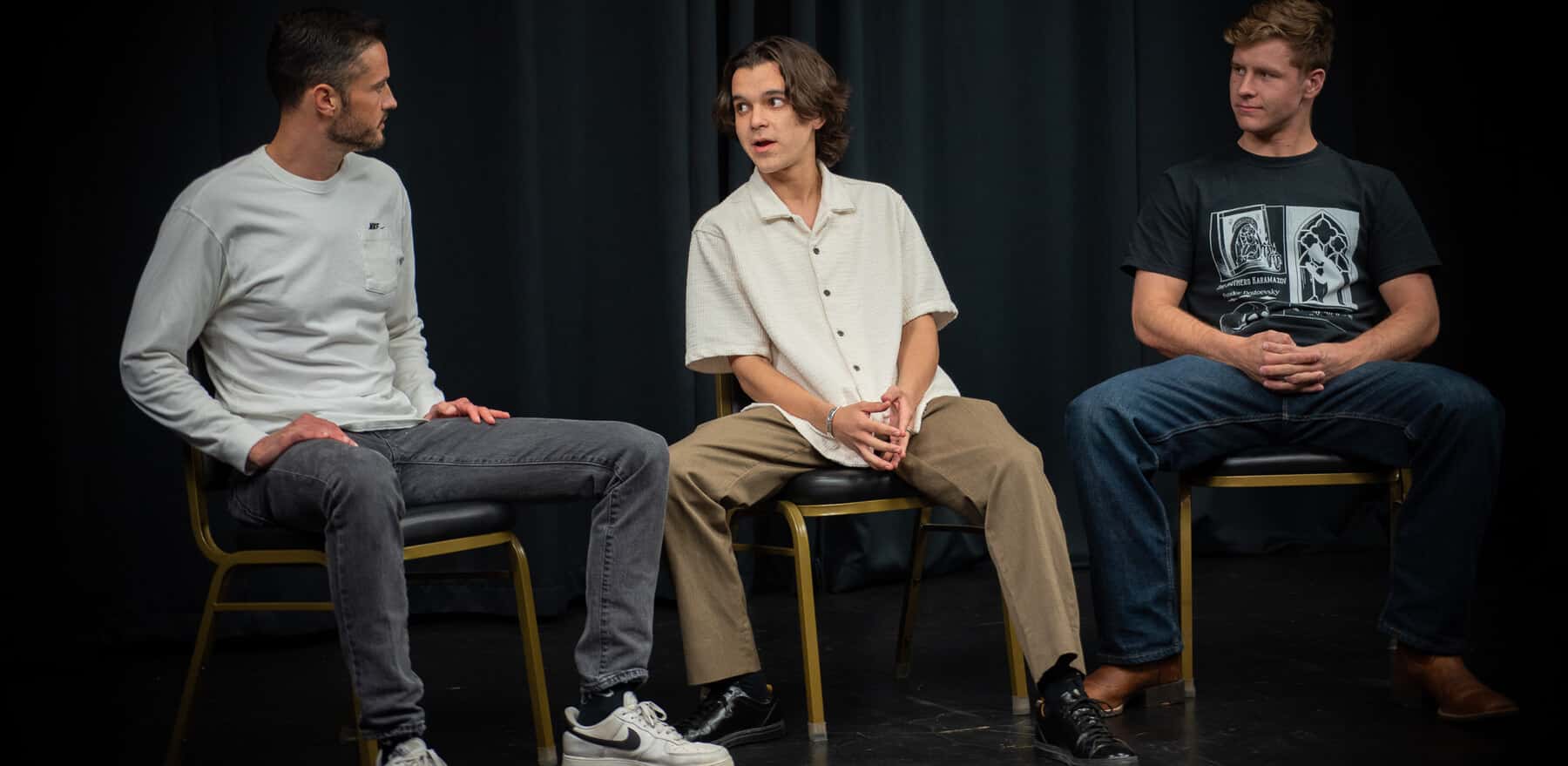 Three students on stage at Dearing Acting Studio, one speaking and two listening